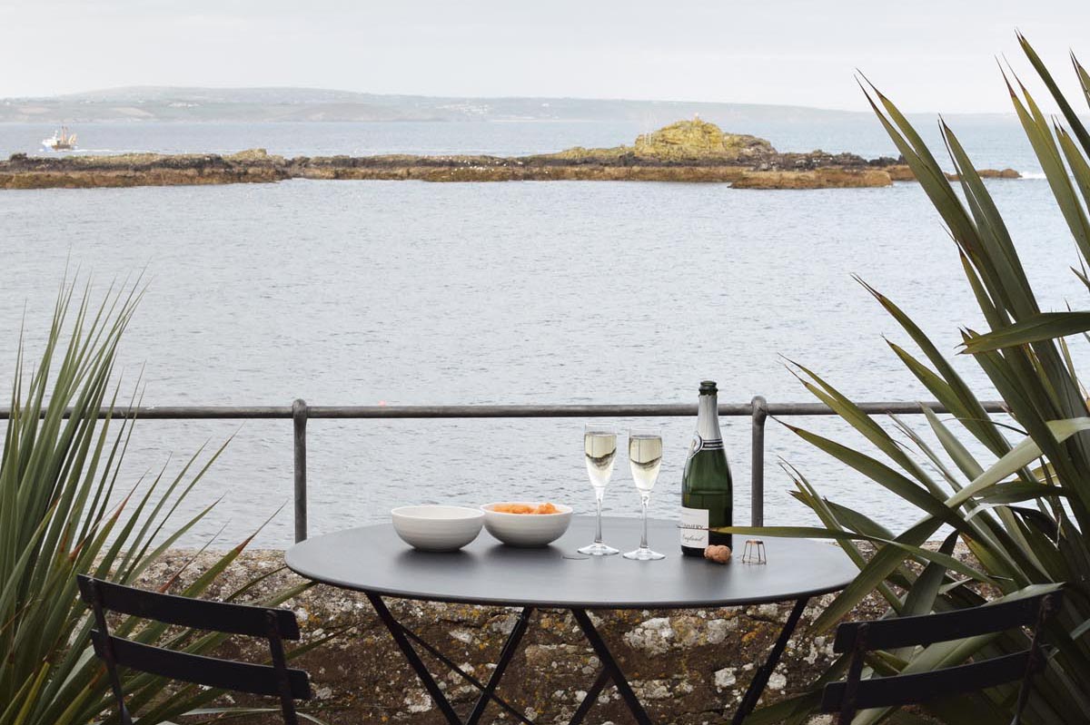 Seaside terrace with bistro table and changes | A relaxed stay at Morvoren - a stylish self-catering cottage with sea views in Mousehole, Cornwall | These Four Walls blog