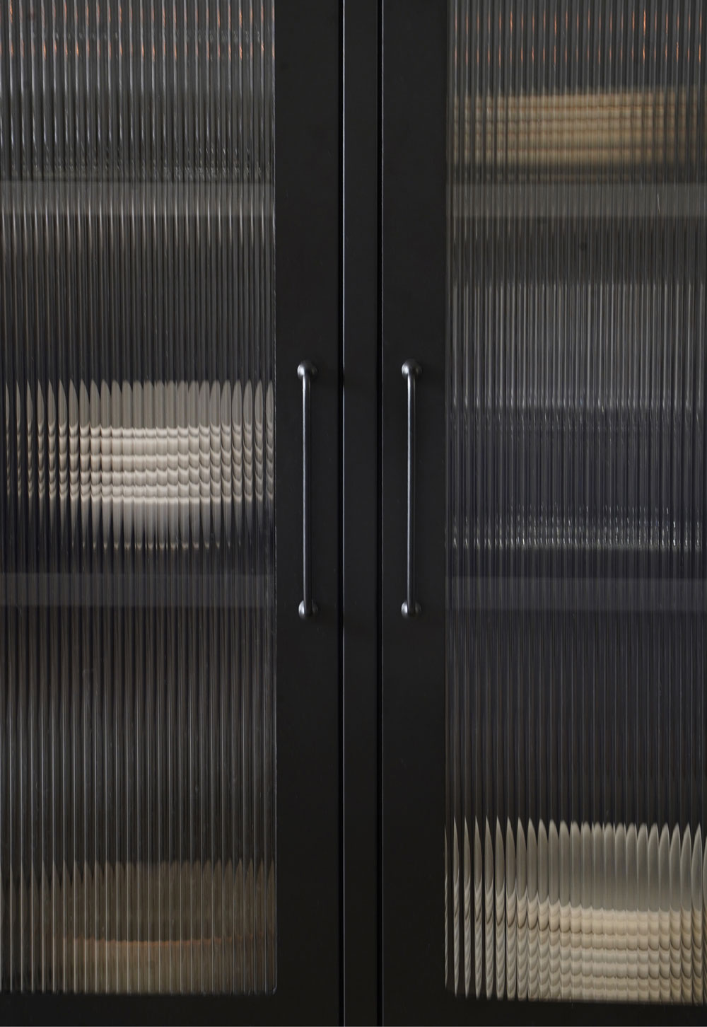 Black reed-fronted display cabinet from Bisley, with rustic-minimalist beige tableware and glassware inside | These Four Walls blog
