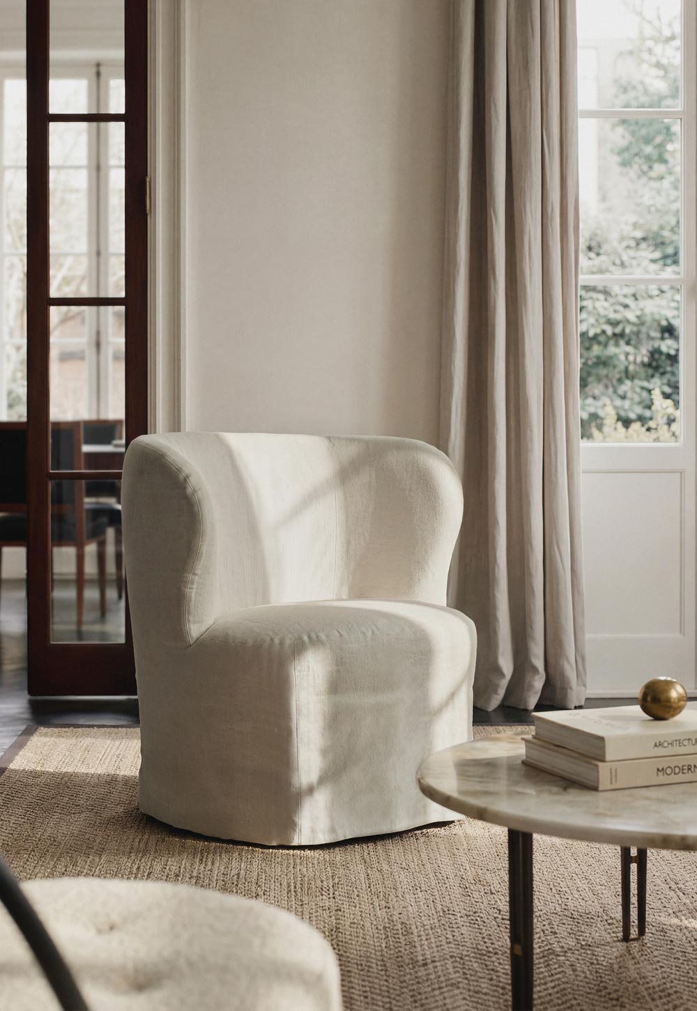 Calm neutral living room with natural materials and beige linen slipcover chair from GUBI's 'Stay' collection | New design finds - July 2026 | These Four Walls blog