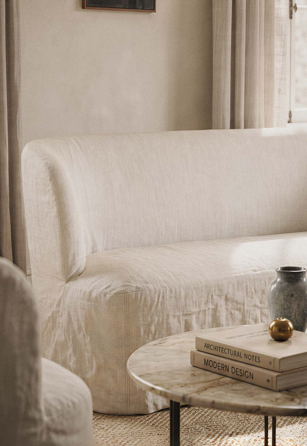 Calm neutral living room with marble table, natural materials and beige linen slipcover sofa from GUBI's 'Stay' collection | New design finds - July 2026 | These Four Walls blog