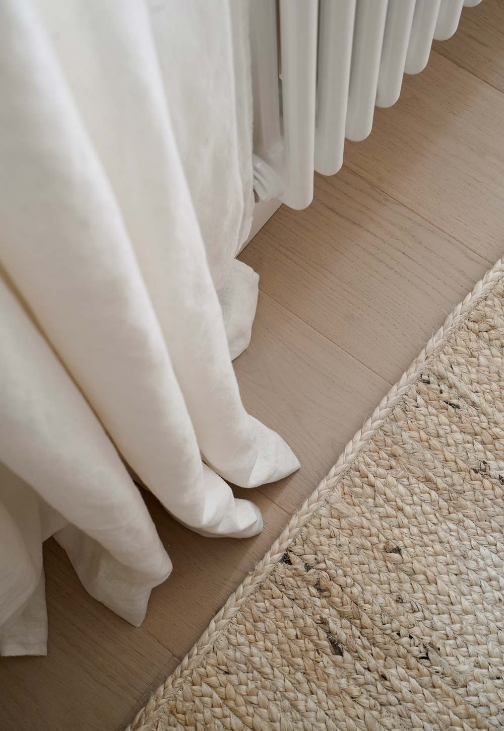Pale oak floor, linen curtains and jute rug in a rustic-minimalist cottage interior | These Four Walls blog