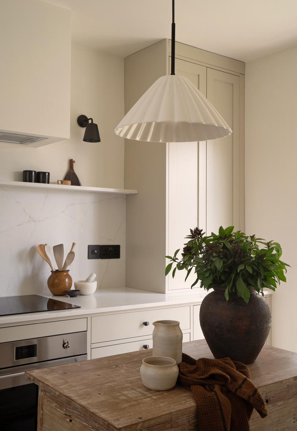 Scalloped ceramic pendant light, beige Shaker units and rustic wooden island unit in a minimalist cottage kitchen | These Four Walls blog