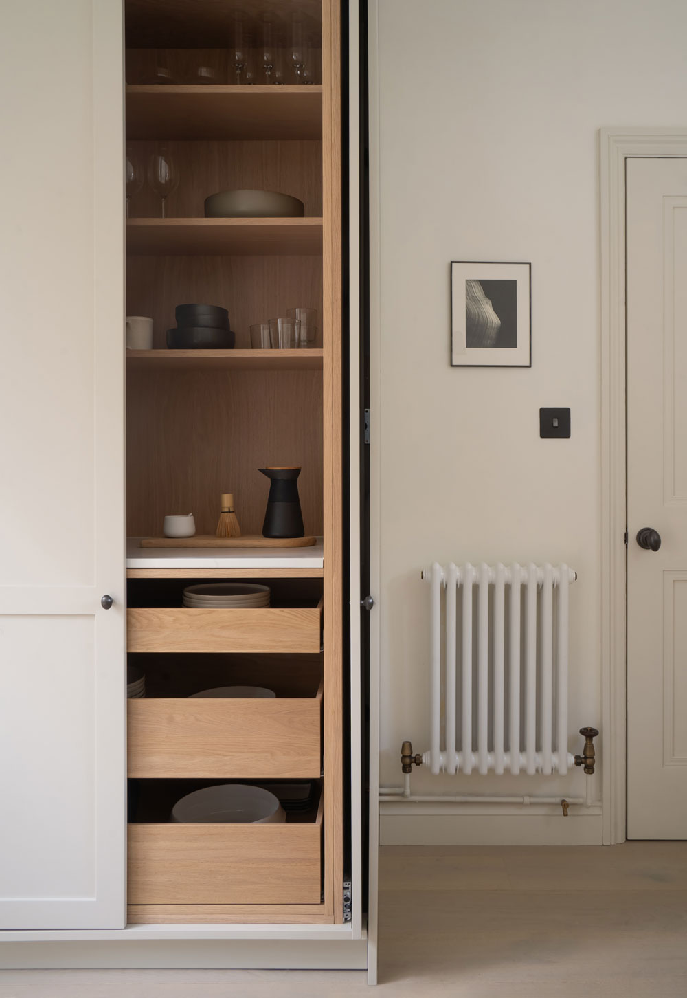 Minimalist cottage kitchen with beige Shaker units and pocket-door larder cupboard with oak interior | These Four Walls blog