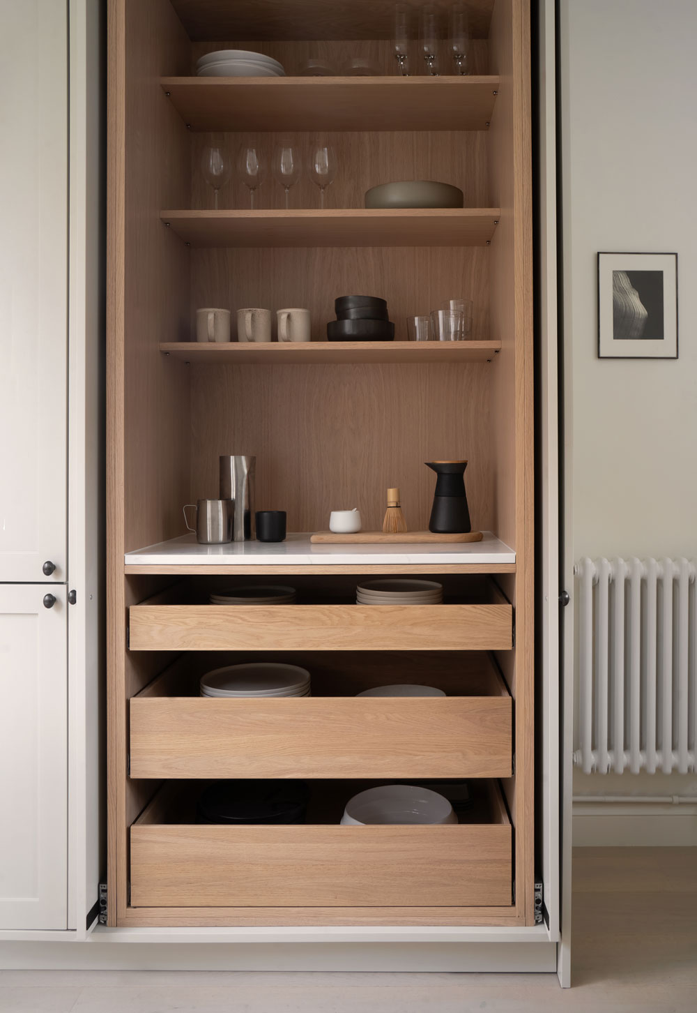 Pocket-door larder cupboard with oak interior in a minimalist cottage kitchen with beige Shaker units | These Four Walls blog